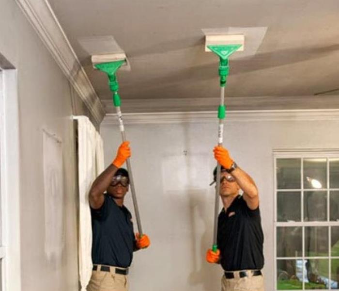 SERVPRO techs cleaning ceiling of soot using special mops
