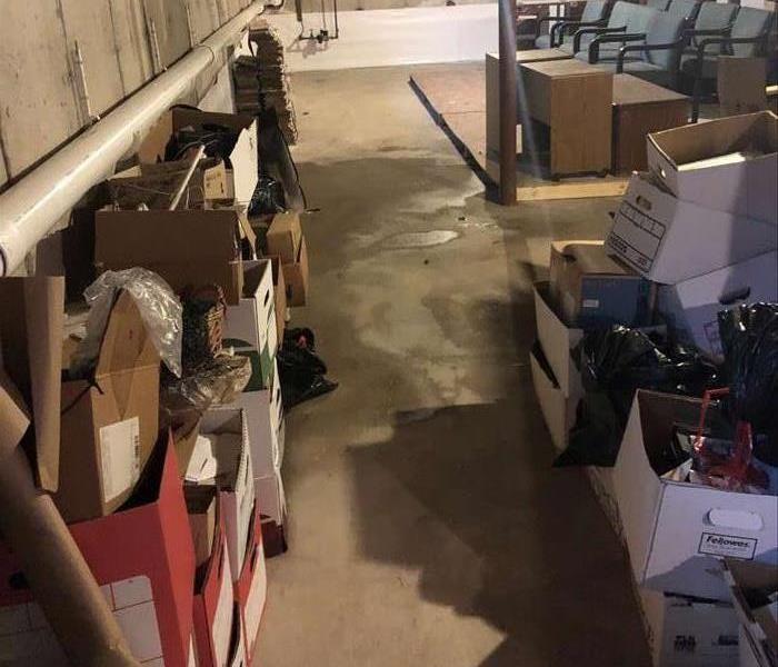 basement with wet floor with boxes of damaged articles piled up on both sides of the picture